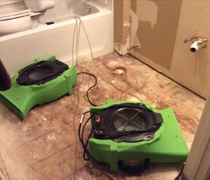Air movers in a bathroom with removed flooring and vanity